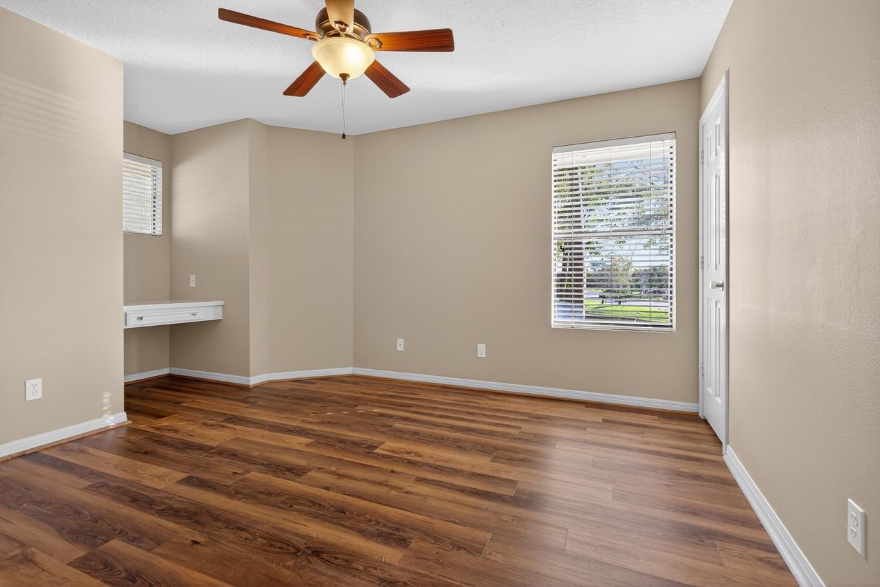 12626 Aries Loop Willis, TX 77318 - Photo 25 of 50 This room features warm wood flooring, neutral walls, and a ceiling fan. It has two windows with blinds for natural light and a small built-in desk area.