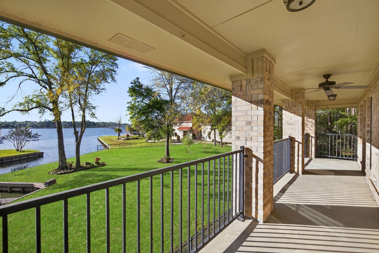 12626 Aries Loop Willis, TX 77318 - Photo 32 of 50 This spacious covered porch offers stunning waterfront views, perfect for relaxation and enjoying the natural scenery. The well-maintained lawn and nearby trees add to the serene atmosphere.