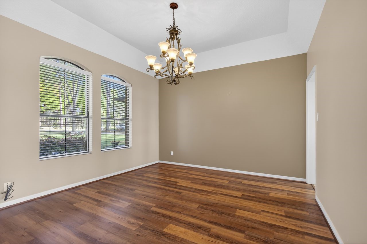 12626 Aries Loop Willis, TX 77318 - Photo 10 of 50 This room features warm wood flooring and neutral walls, accented by a stylish chandelier. Large windows provide ample natural light, creating a bright and inviting space.