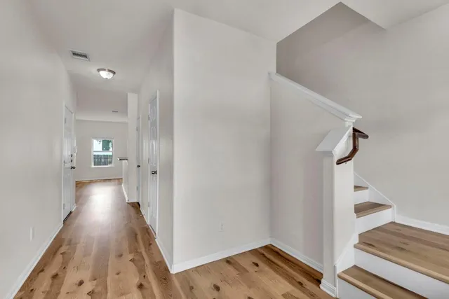 a view of a hallway with wooden floor and staircase
