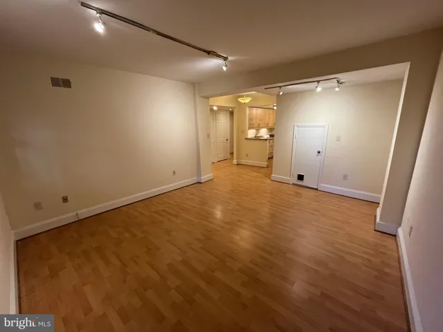 an empty room with wooden floor and mirror