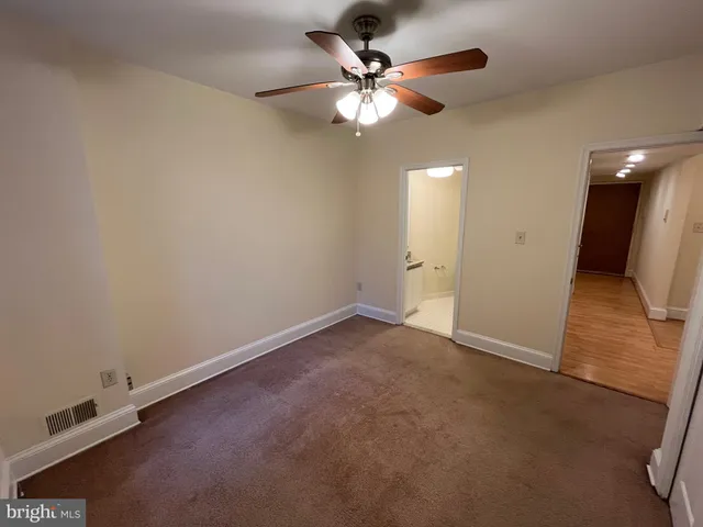 an empty room with a ceiling fan and a rug