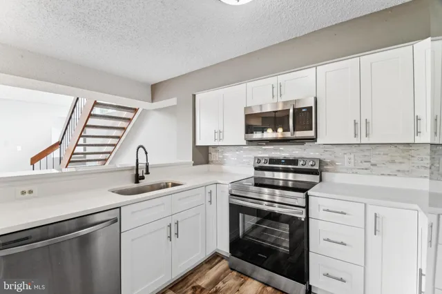 a kitchen with white cabinets appliances and a sink