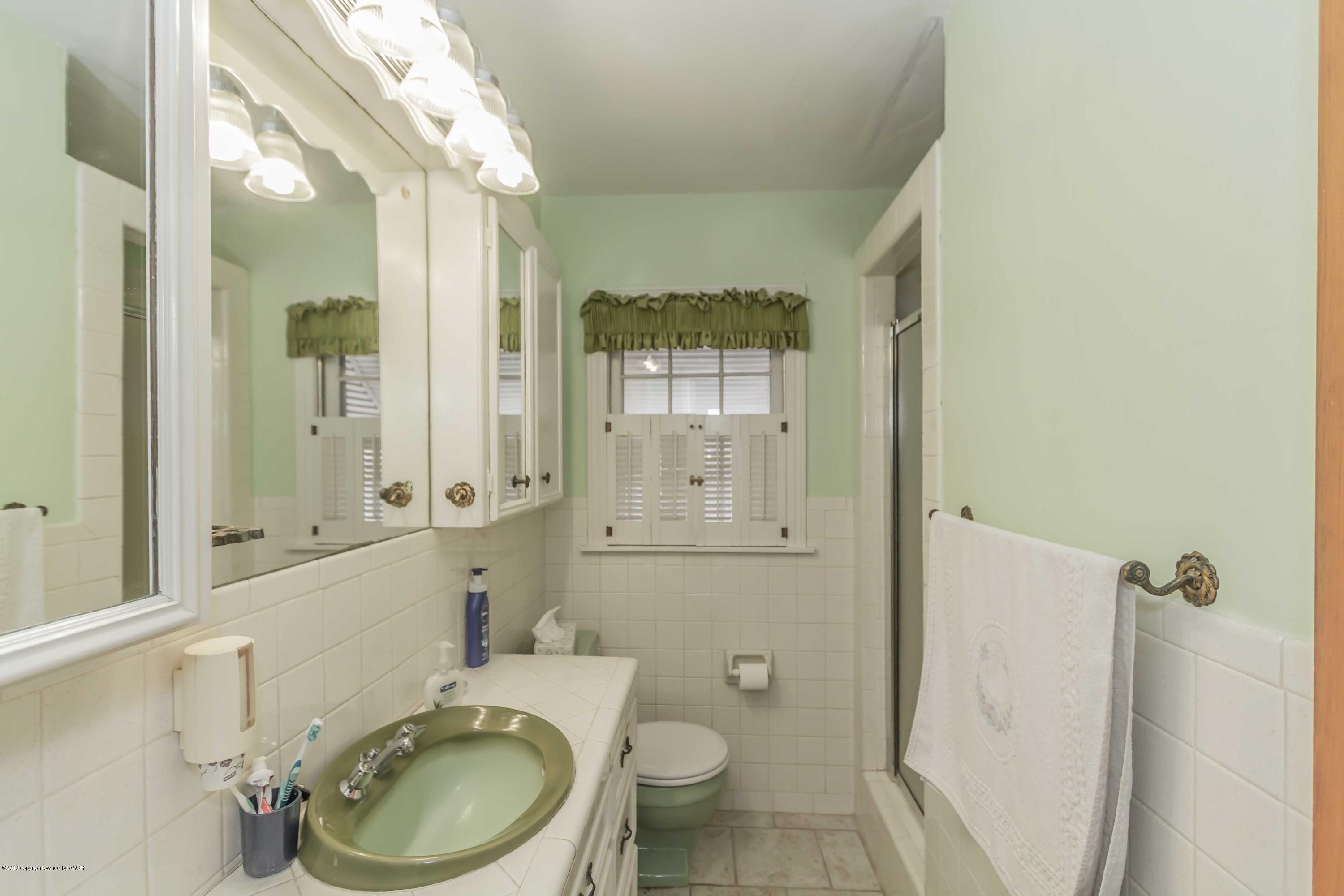 3613 Cline Road Amarillo, TX 79110 - Photo 18 of 36 a bathroom with a granite countertop toilet a sink and a mirror