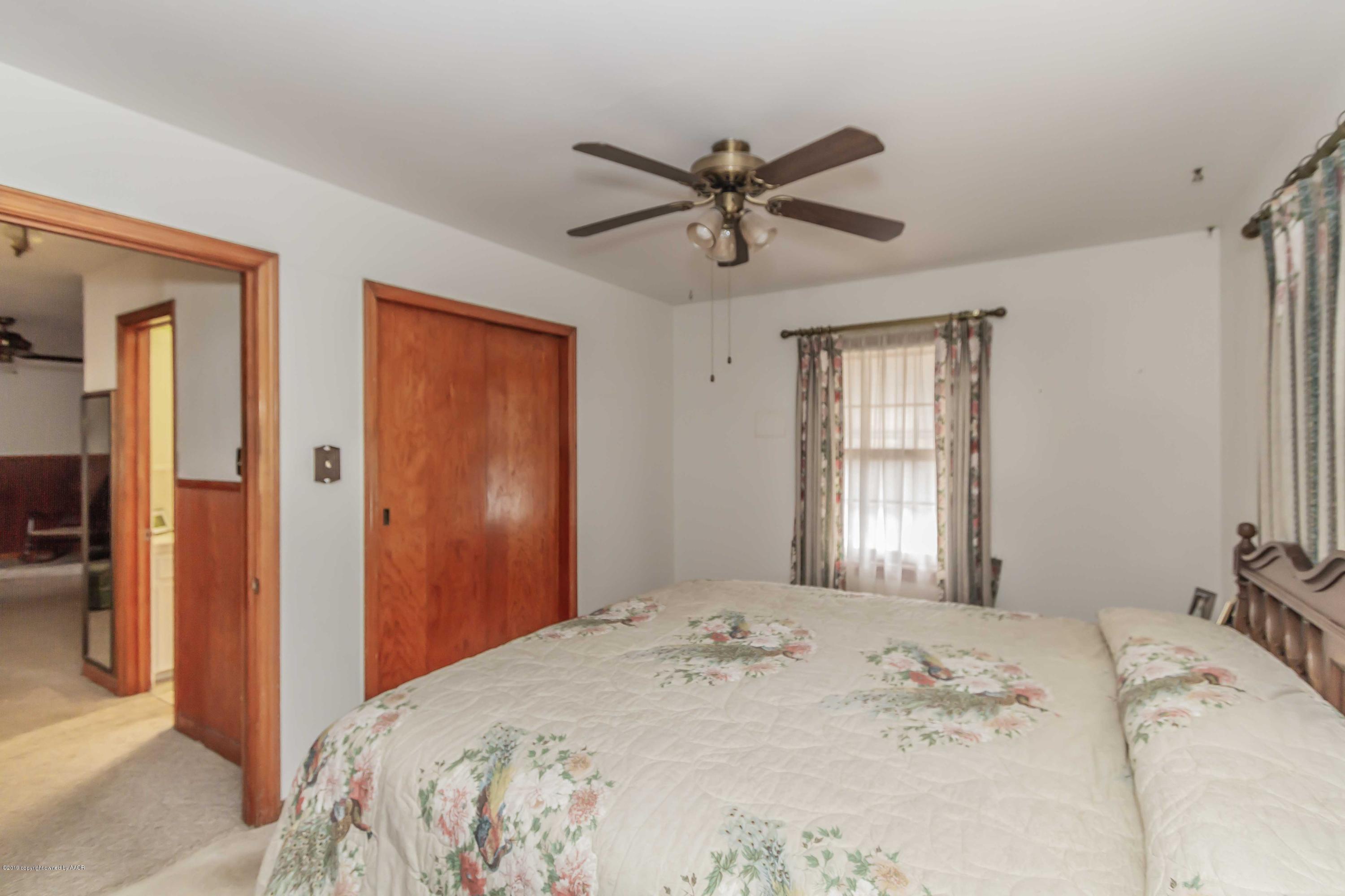 3613 Cline Road Amarillo, TX 79110 - Photo 22 of 36 a bedroom with a large bed and a chandelier