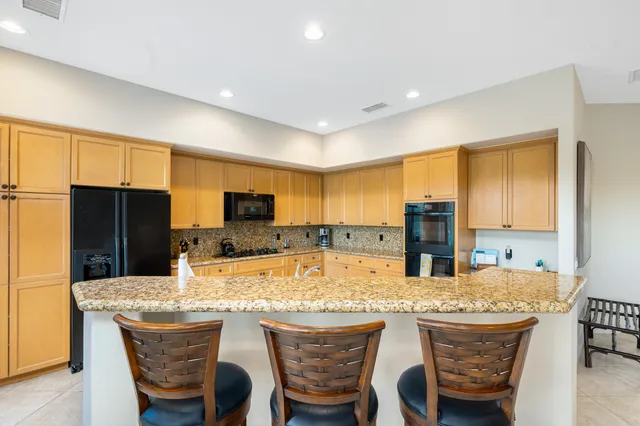 a kitchen with granite countertop kitchen island refrigerator stove microwave and cabinets