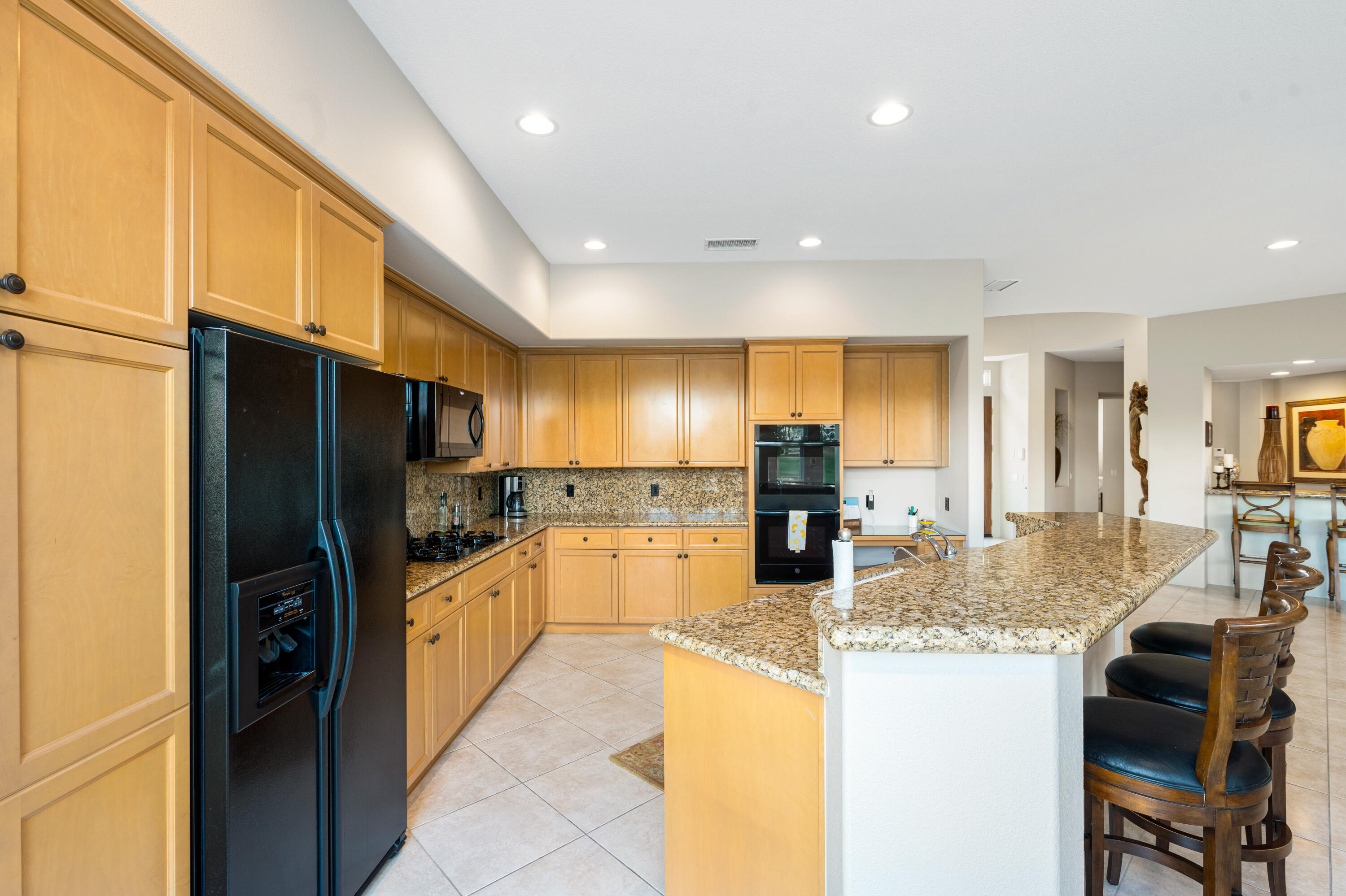 80824 Hermitage La Quinta, CA 92253 - Photo 20 of 49 a kitchen with granite countertop kitchen island refrigerator stove microwave and cabinets