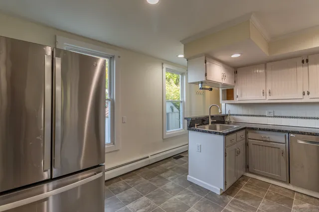 a kitchen with stainless steel appliances granite countertop a refrigerator a sink and white cabinets