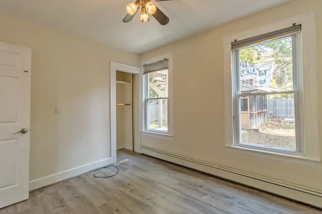 a view of an empty room with a window and wooden floor
