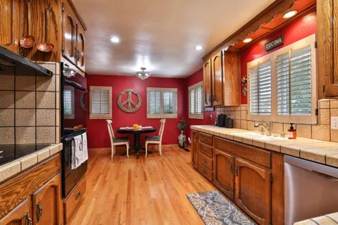 a kitchen with stainless steel appliances granite countertop a sink a stove and wooden floors