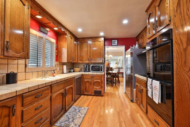 a kitchen with stainless steel appliances granite countertop sink stove top oven and cabinets