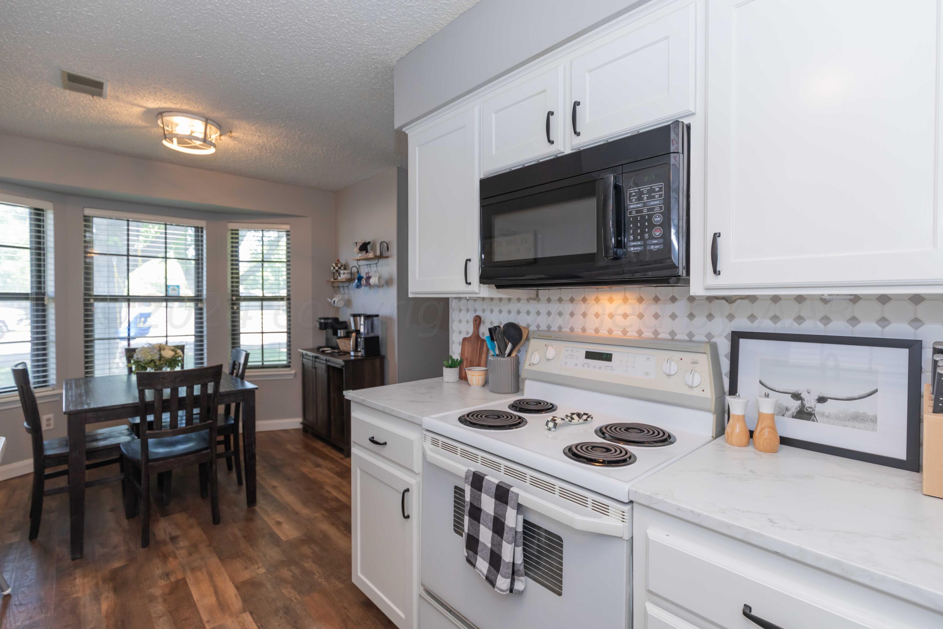 5804 Oakman Drive Amarillo, TX 79109 - Photo 14 of 48 a kitchen with a stove a microwave and wooden floor