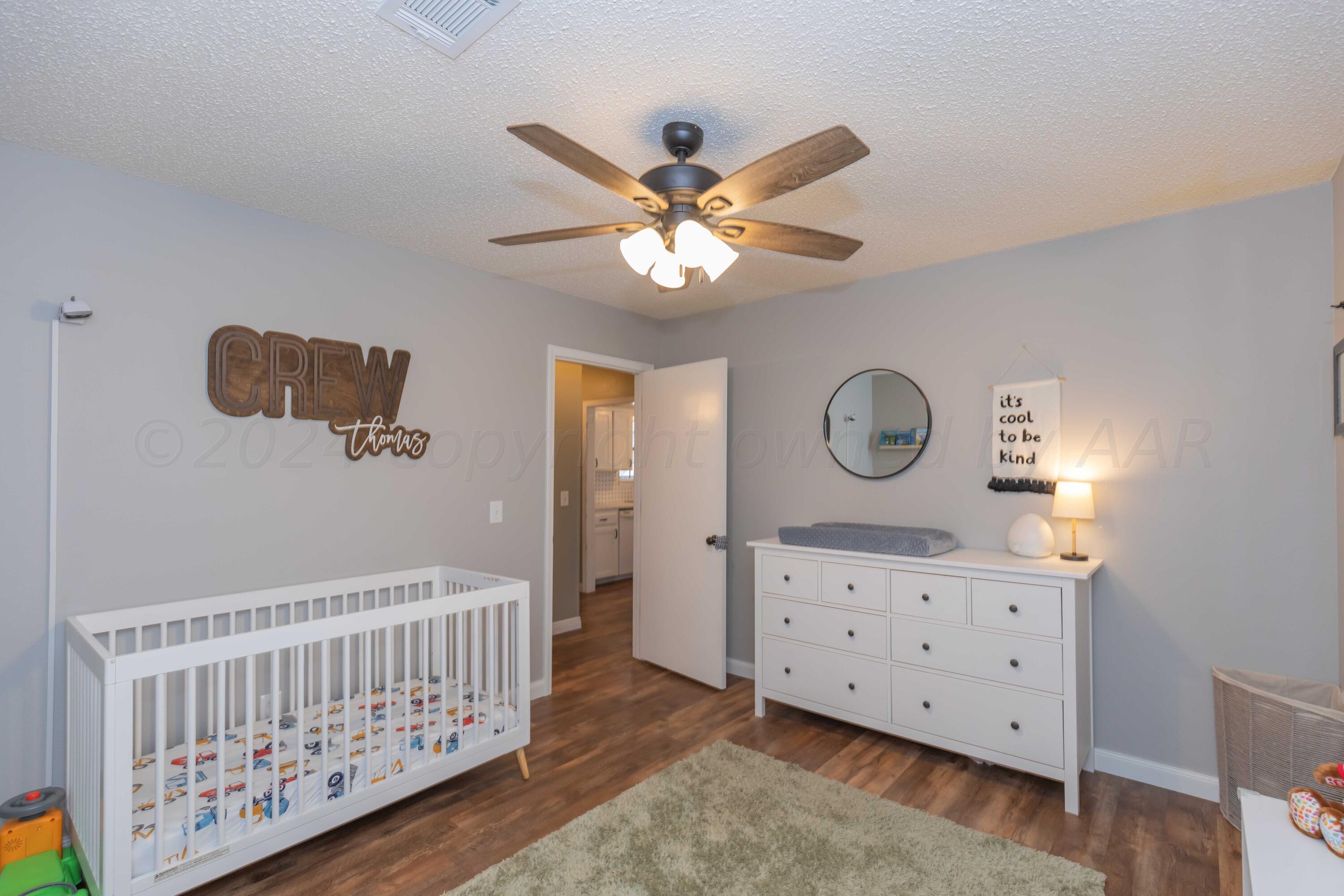 5804 Oakman Drive Amarillo, TX 79109 - Photo 39 of 48 a bedroom with a baby bed a chandelier and a dresser