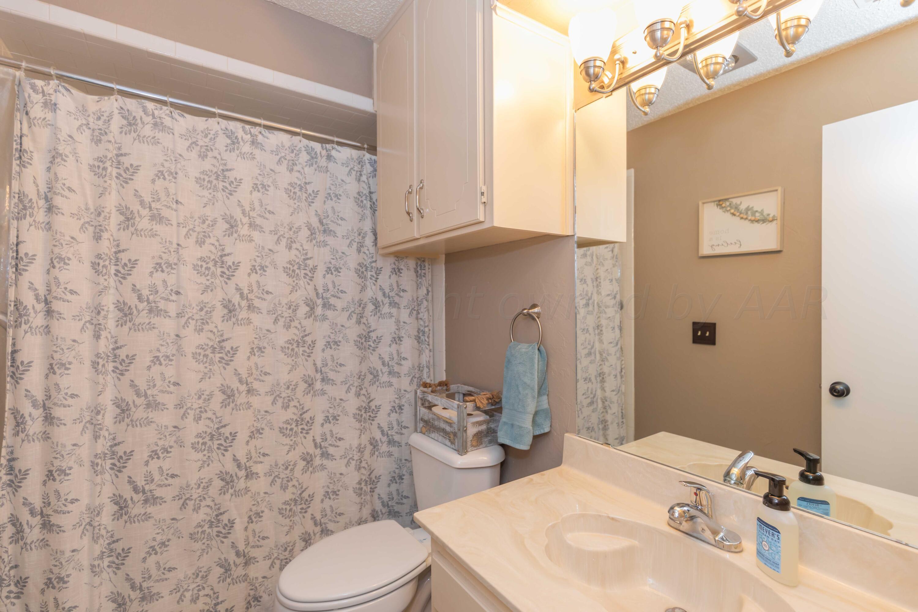 5804 Oakman Drive Amarillo, TX 79109 - Photo 40 of 48 a bathroom with a sink a toilet and a mirror