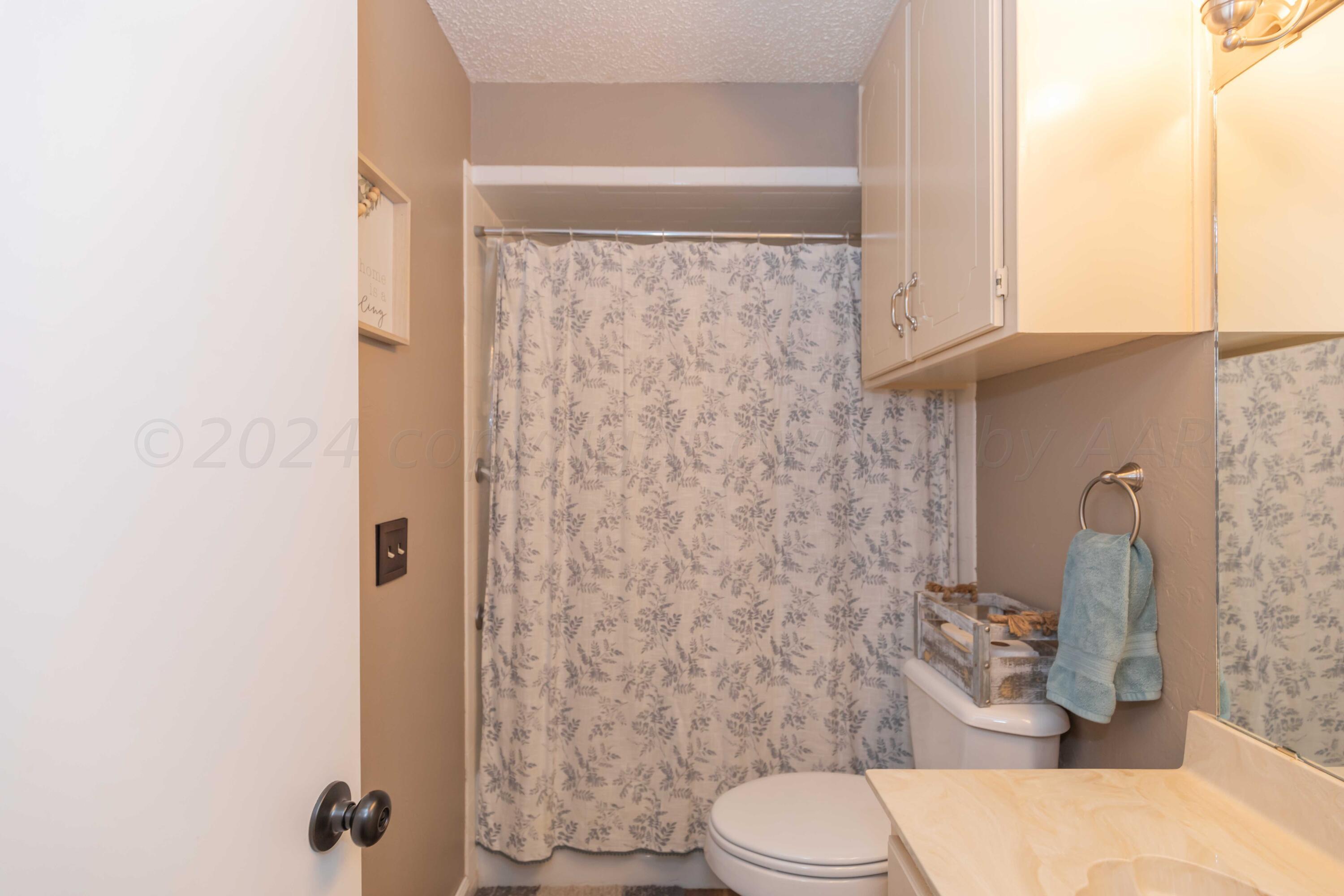 5804 Oakman Drive Amarillo, TX 79109 - Photo 41 of 48 a white toilet sitting next to a shower curtain