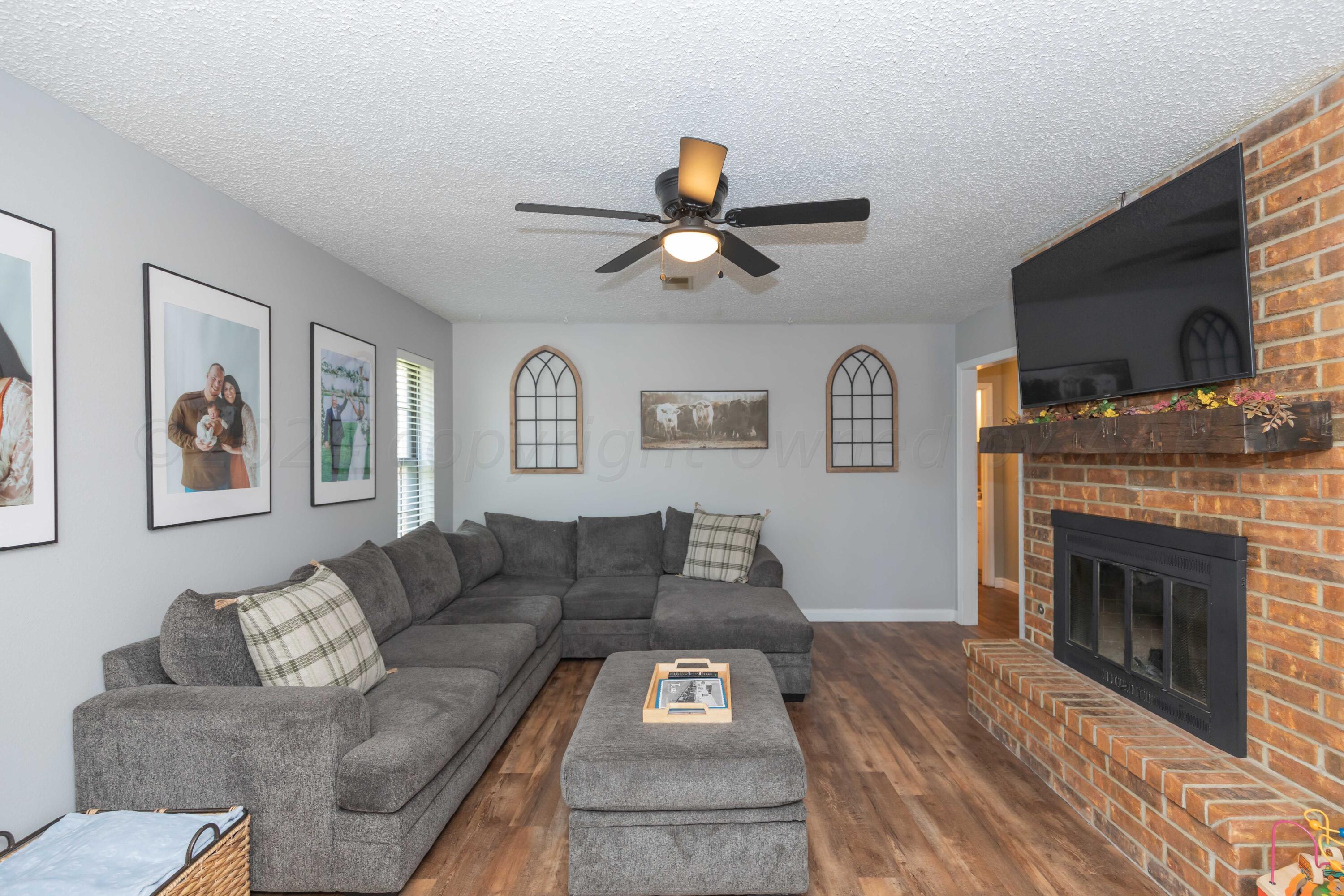 5804 Oakman Drive Amarillo, TX 79109 - Photo 5 of 48 a living room with furniture a flat screen tv and a fireplace