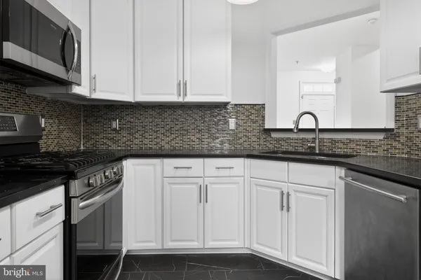 a kitchen with granite countertop white cabinets and a stove