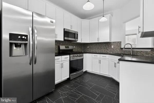 a white kitchen with granite countertop stainless steel appliances