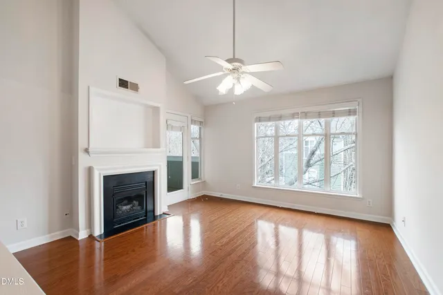 an empty room with windows fireplace and wooden floor