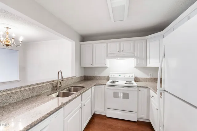 a kitchen with white cabinets white stainless steel appliances and sink