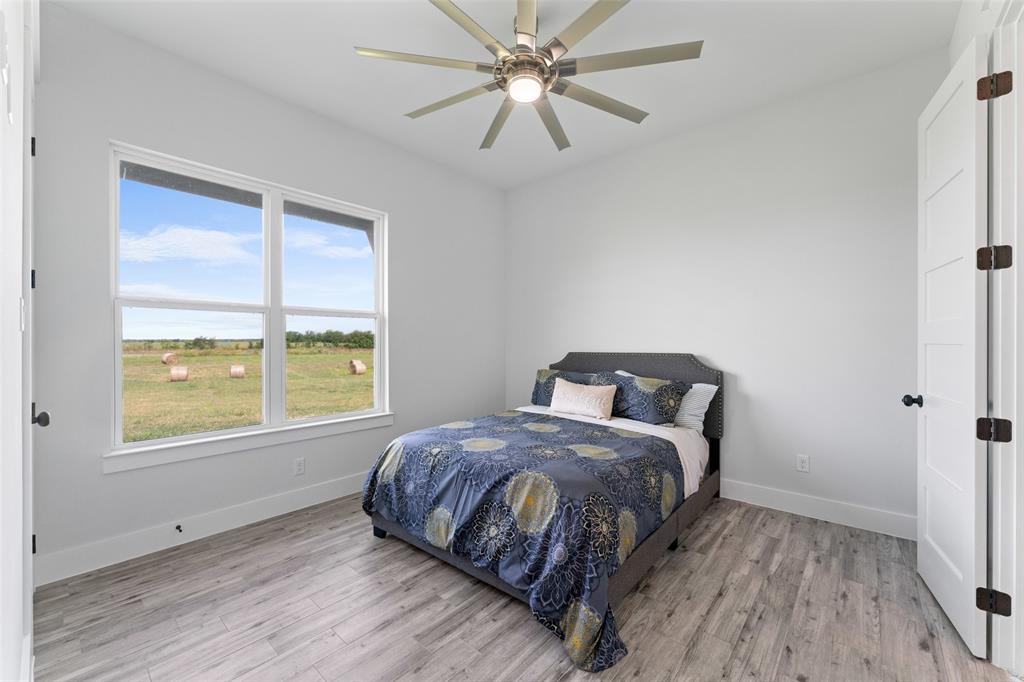 4411 Fm 751 Wills Point Wills Point, TX 75169 - Photo 27 of 40 Bright interior space featuring a large window with white trim, wood-finish flooring, a contemporary ceiling fan with integrated lighting, and a white paneled door with dark hardware