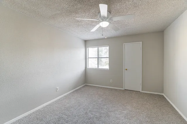 an empty room with windows and fan