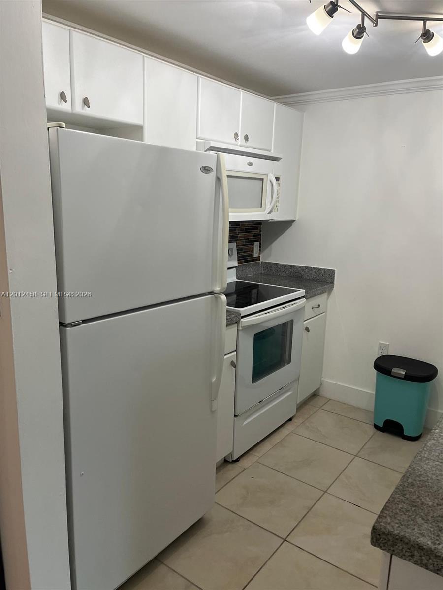 2740 Southwest 28th Terrace, Unit 203 Miami, FL 33133 - Photo 11 of 14 a white refrigerator freezer and a stove sitting inside of a kitchen with granite countertop white cabinets