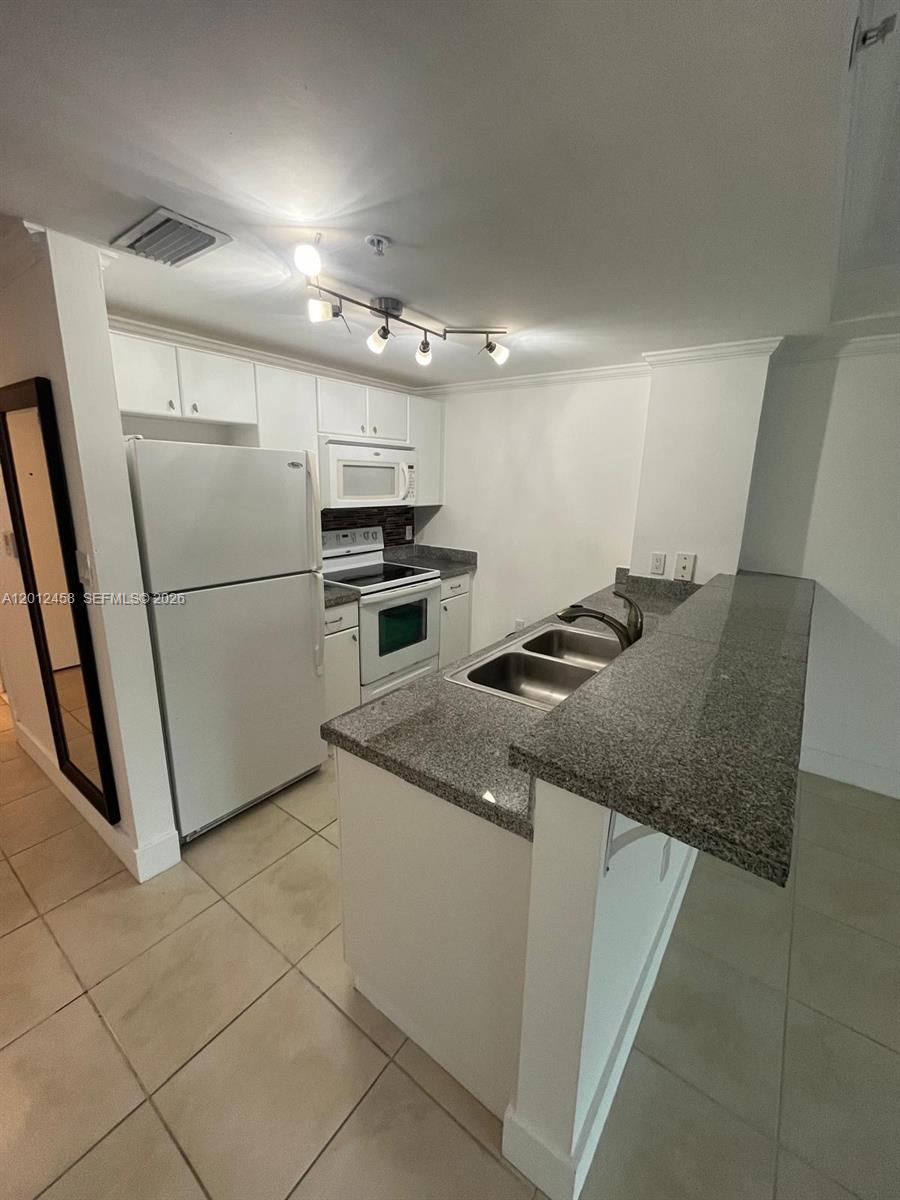 2740 Southwest 28th Terrace, Unit 203 Miami, FL 33133 - Photo 8 of 14 a kitchen with granite countertop a refrigerator and a stove