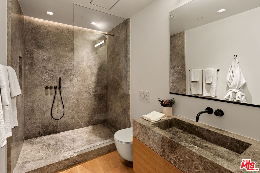 1663 Summitridge Drive Beverly Hills, CA 90210 - Photo 31 of 41 a bathroom with a granite countertop sink a toilet and a shower