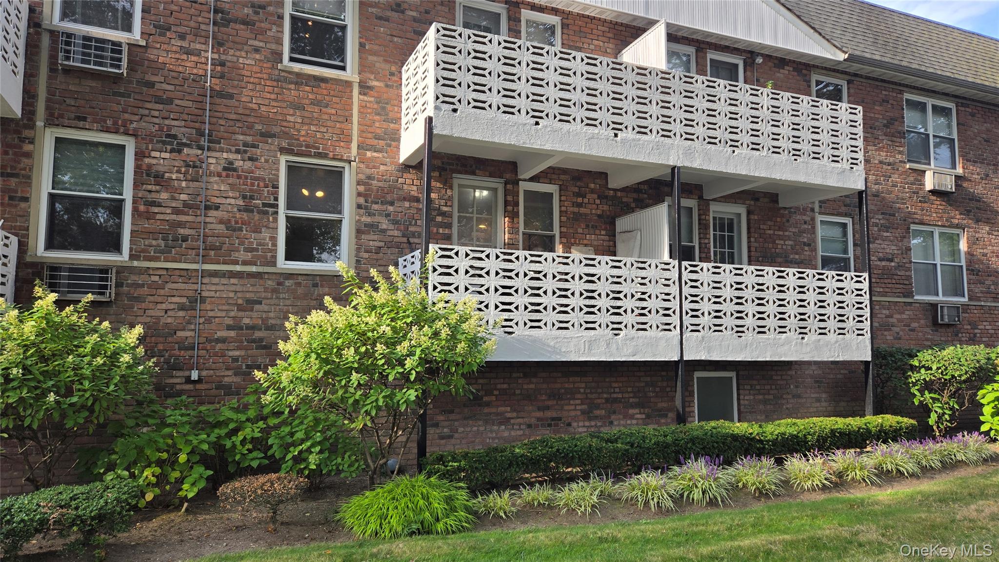 30 Daley Place, Unit 146 Lynbrook, NY 11563 - Photo 3 of 24 a view of a brick house with a yard potted plants and large tree