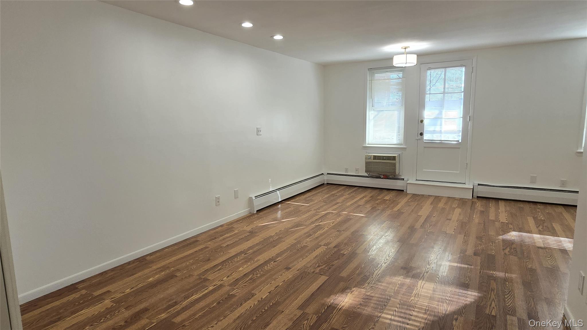 30 Daley Place, Unit 146 Lynbrook, NY 11563 - Photo 7 of 24 an empty room with wooden floor and windows