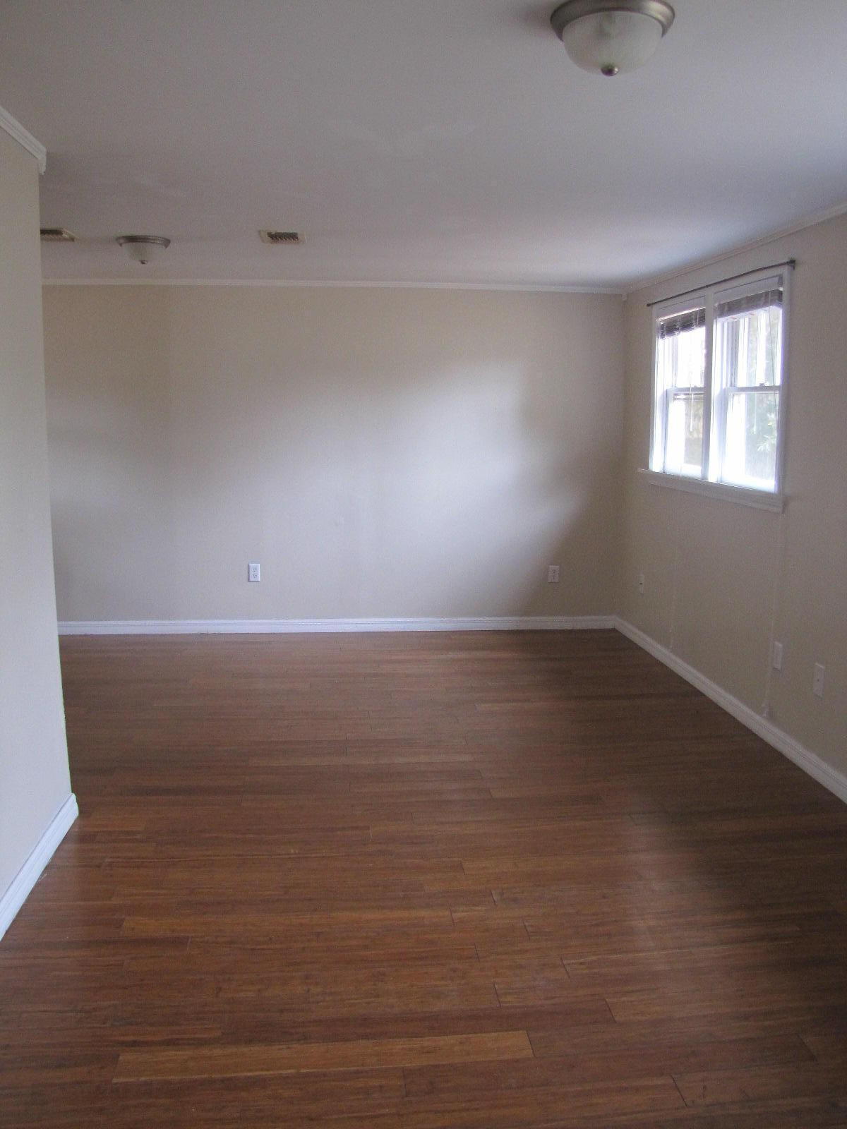 451 East 3rd Avenue Crestview, FL 32536 - Photo 4 of 8 a view of an empty room with wooden floor and a window