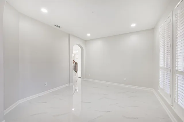 a view of an empty room and window with a chandelier fan