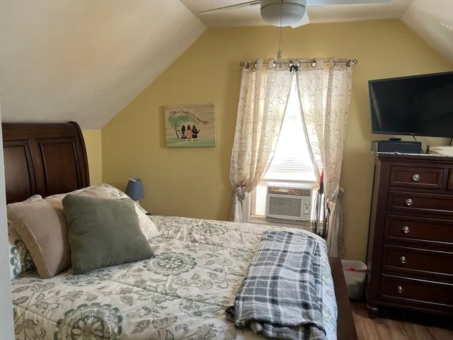 a bedroom with a bed and a flat tv screen on dresser