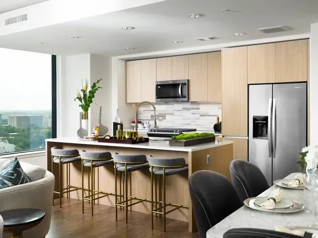 a kitchen with stainless steel appliances a dining table chairs refrigerator and microwave