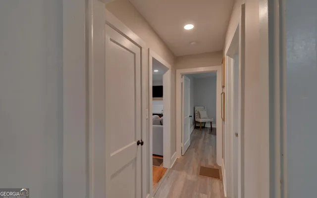 a view of a hallway with wooden floor and a bathroom