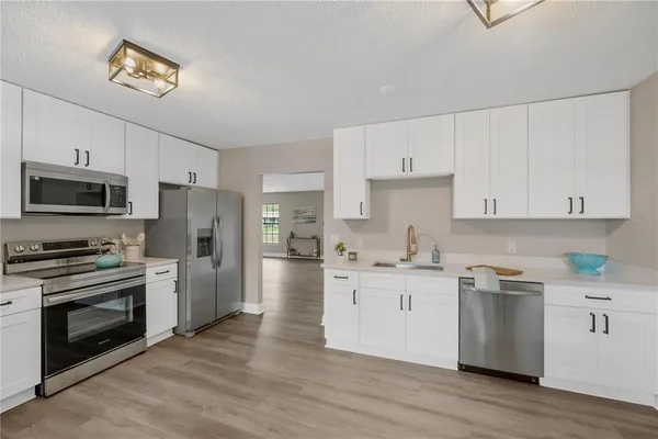a kitchen with stainless steel appliances a stove top oven a refrigerator a sink and dishwasher with wooden floor