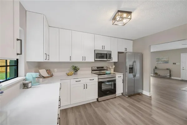 a kitchen with stainless steel appliances a stove top oven a refrigerator a sink and dishwasher with wooden floor