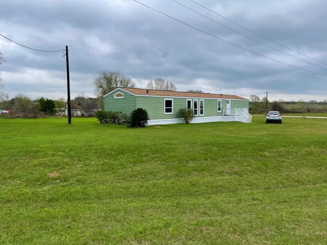 a view of a house with a big yard and a large trees with a big yard