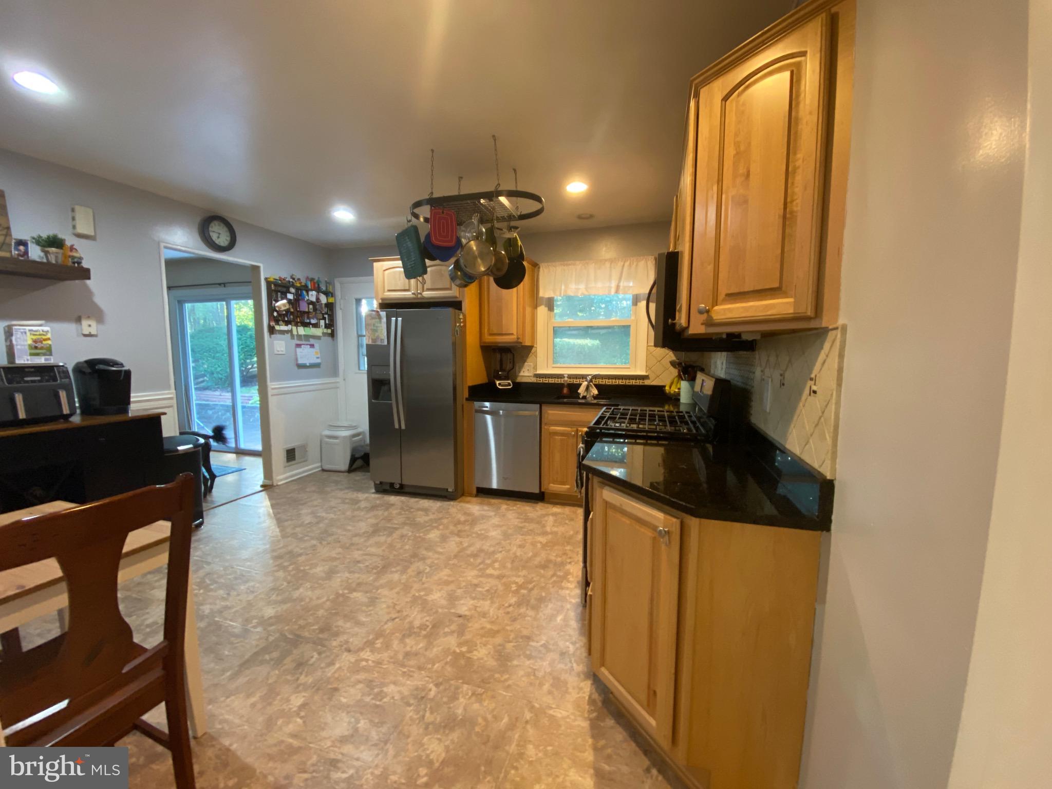 8614 Arley Drive Springfield, VA 22152 - Photo 6 of 24 a kitchen with stainless steel appliances granite countertop a refrigerator a stove a sink a dining table and chairs with wooden floor
