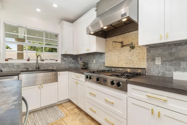 a kitchen with stainless steel appliances granite countertop a stove and a white cabinets