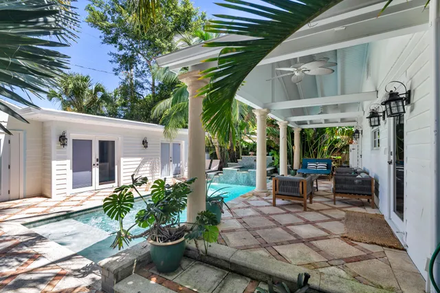 a view of a patio with table and chairs potted plants and floor to ceiling window