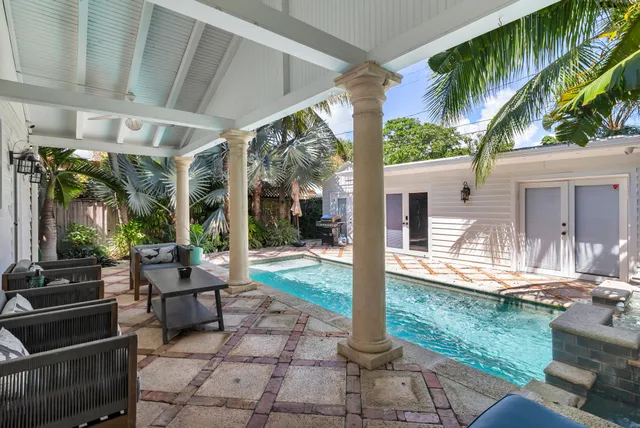 a view of a patio with table and chairs potted plants and floor to ceiling window
