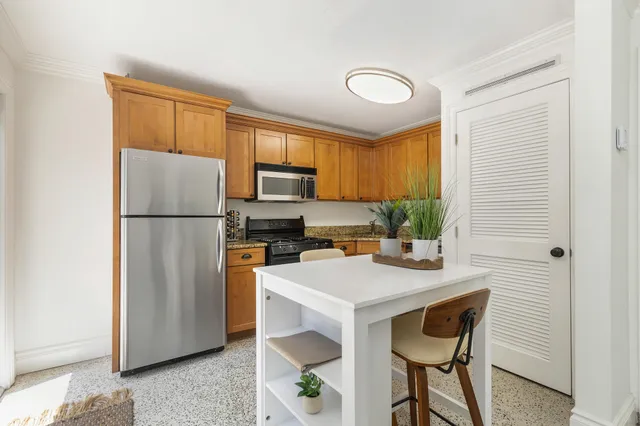 a kitchen with a refrigerator a stove a sink cabinets and a dining table