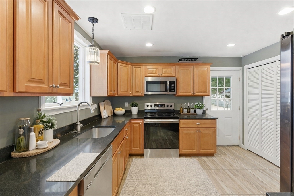106 Baldwin Avenue Framingham, MA 01701 - Photo 4 of 13 a kitchen with stainless steel appliances granite countertop a stove top oven a sink dishwasher a dining table and chairs with wooden floor