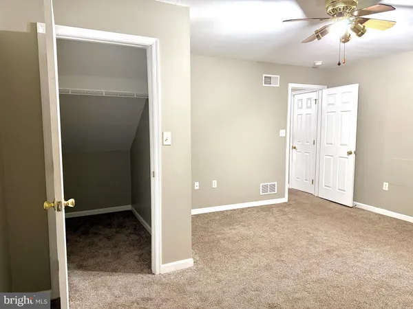 an empty room with closet and a chandelier fan
