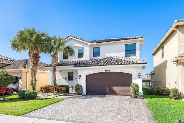 a front view of a house with a garden and palm trees