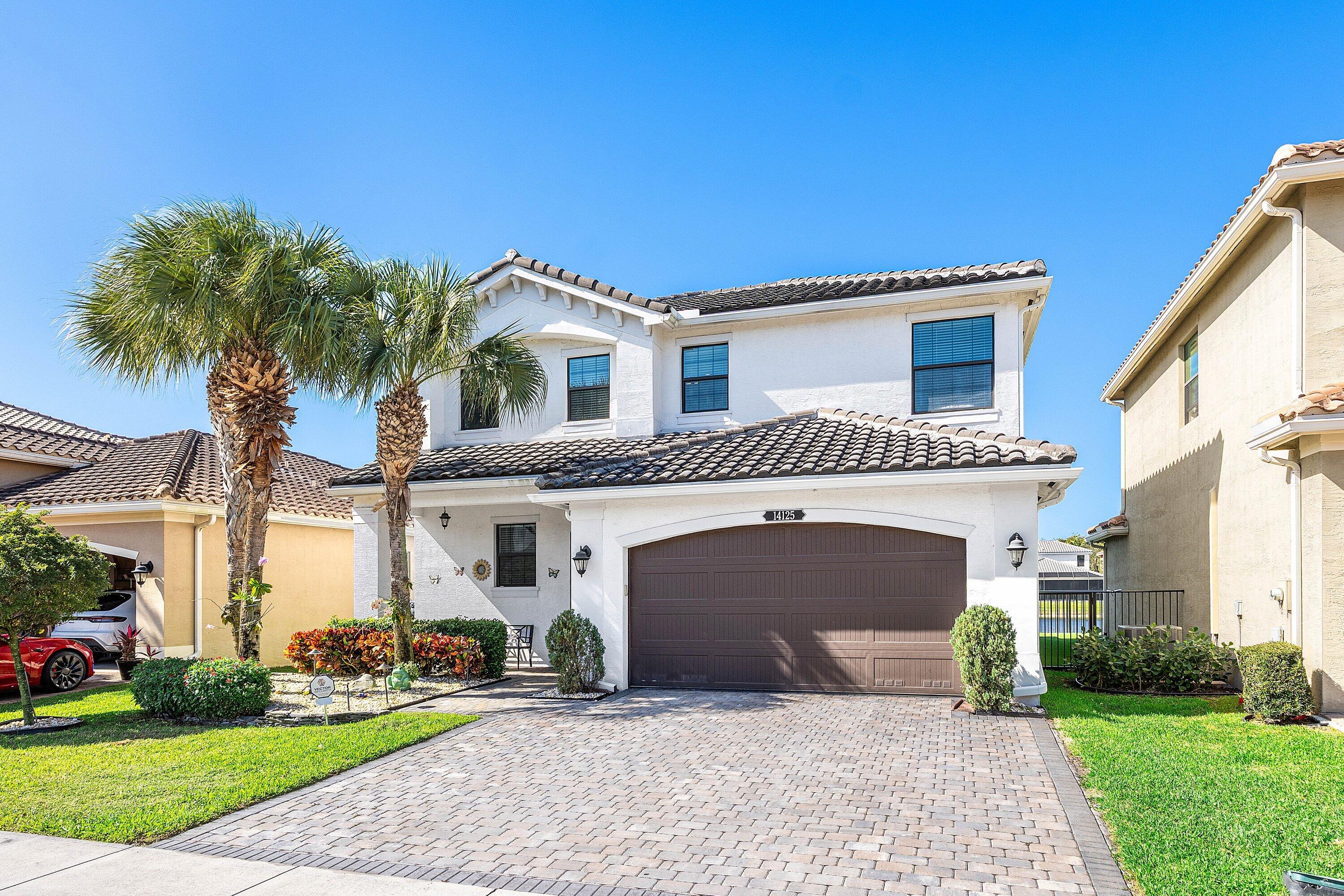 14125 Rock Salt Road Delray Beach, FL 33446 - Photo 2 of 55 a front view of a house with a garden and palm trees