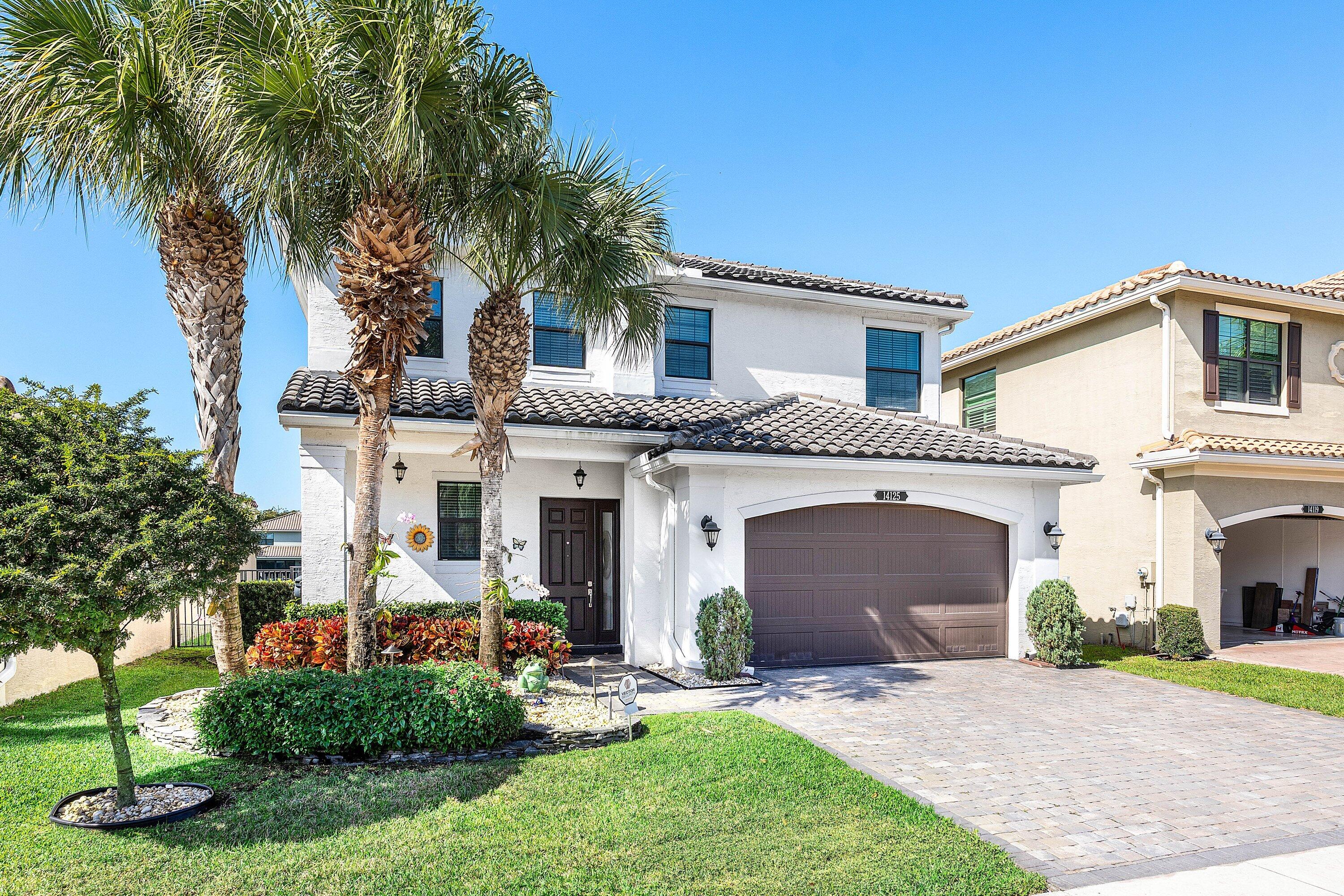 14125 Rock Salt Road Delray Beach, FL 33446 - Photo 3 of 55 a front view of a house with a garden and palm trees