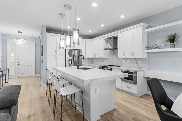 a kitchen with kitchen island stainless steel appliances a table chairs sink and cabinets